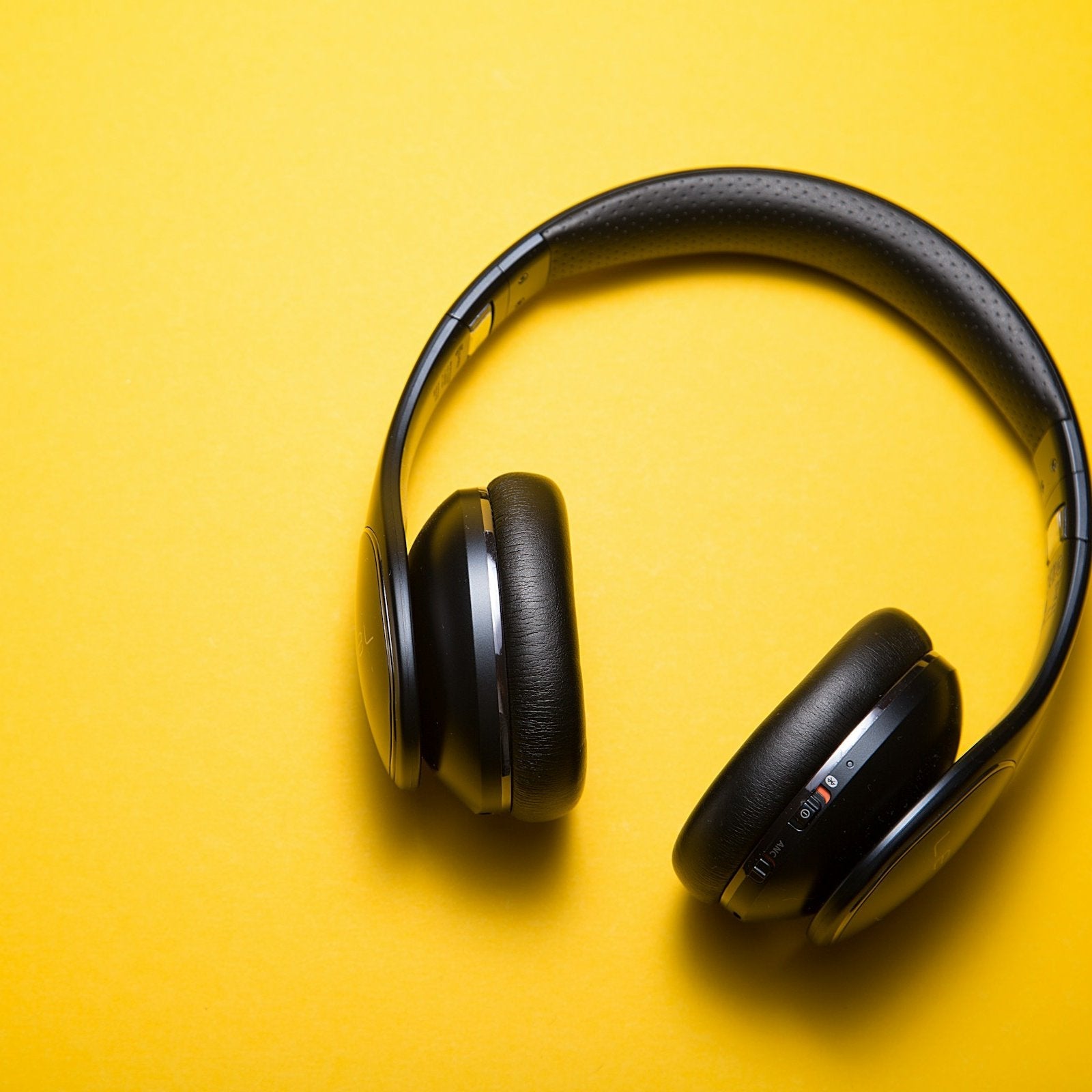 Black wireless headphones on a yellow background