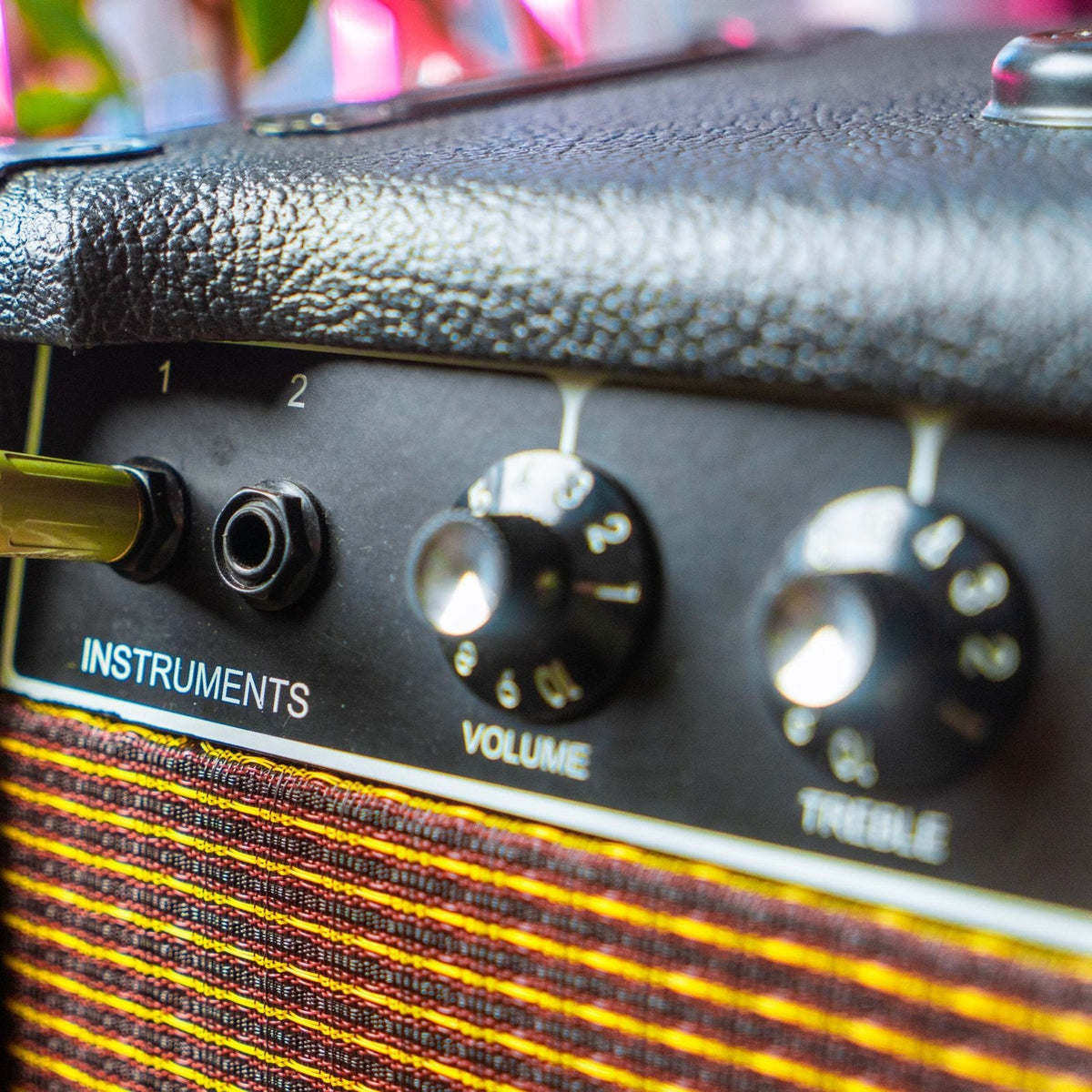 Close-up of amplifier volume and treble knobs with instrument cable
